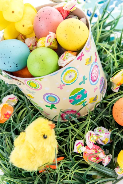 Ostereier mit bunten Eiern, Bonbons und gelben Küken — Stockfoto