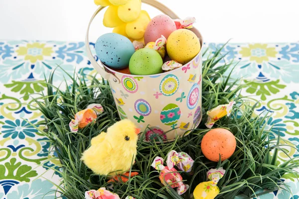 Balde de Páscoa com ovos coloridos, doces e pintinhos amarelos — Fotografia de Stock