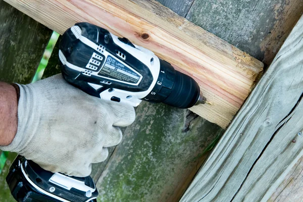 adam ahşap çit onarım için delik delme