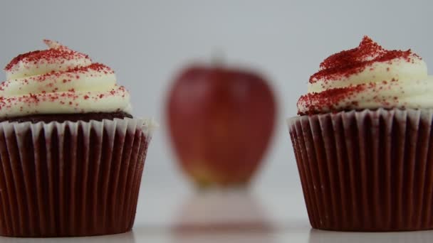 健康食品のオプション。赤いビロードのカップケーキに焦点を当てたが起動し、赤いリンゴに移行 — ストック動画
