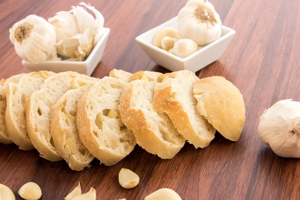 Fresh baked loaf of bread with whole cloves of roasted garlic — Stock Photo, Image