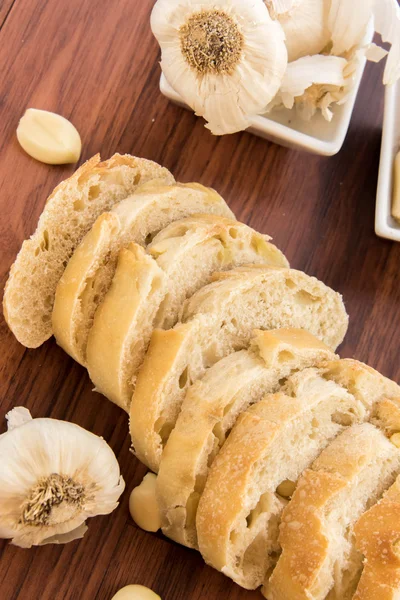 Fresh baked loaf of bread with whole cloves of roasted garlic — Stock Photo, Image