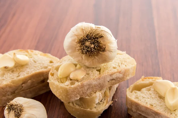 Fresh baked loaf of bread with whole cloves of roasted garlic — Stock Photo, Image