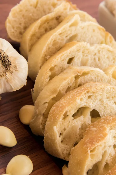 Fresh baked loaf of bread with whole cloves of roasted garlic — Stock Photo, Image