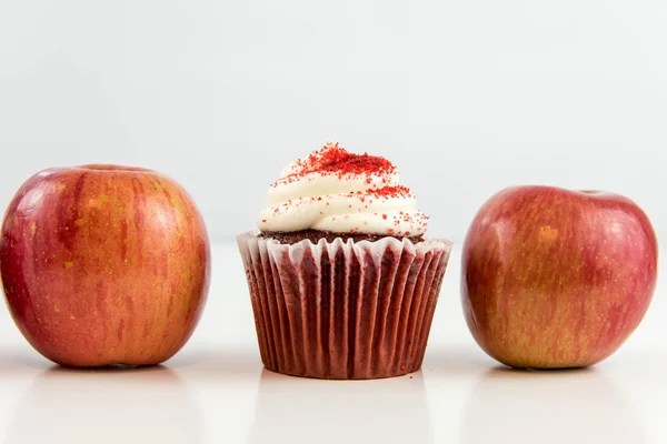 Red apple vs red velvet cupcake — Stock Photo, Image