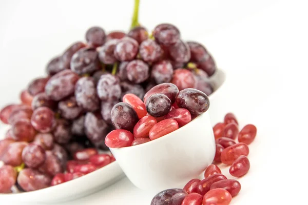 Purple grapes vs purple jelly beans — Stock Photo, Image