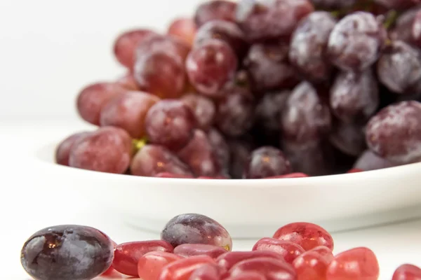 Purple grapes vs purple jelly beans — Stock Photo, Image