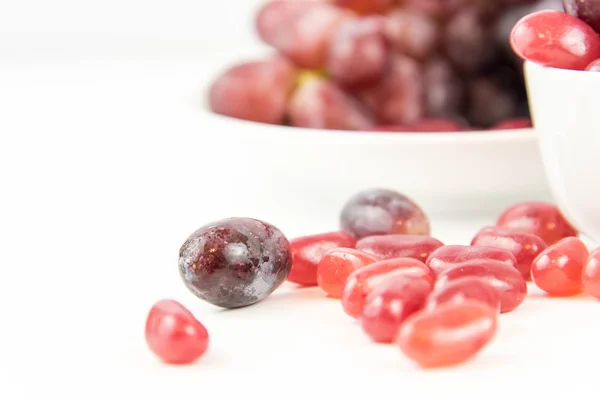 Purple grapes vs purple jelly beans — Stock Photo, Image