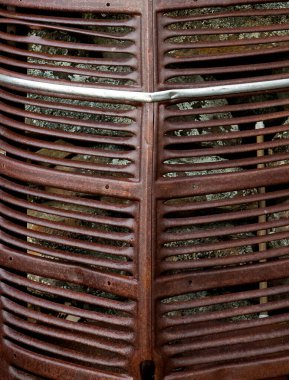 Paslı, eski bir araba ızgarası taş bir duvara yığılmış.