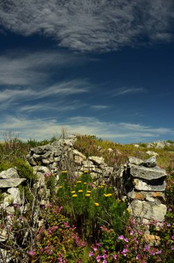 Dramatik mavi ve bulutlu gökyüzüne karşı eski taştan bir kraal duvar