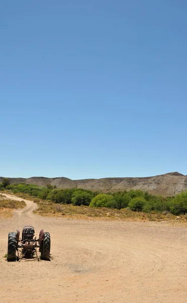 Eski bir traktör Güney Afrika 'da, Karoo' da toprak bir yola park etmiş.