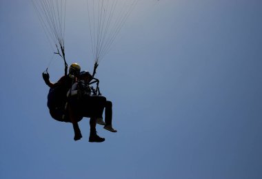 Tanımlanamayan siluet ikili paraglider ve mavi gökyüzünde asılı duran yolcusu