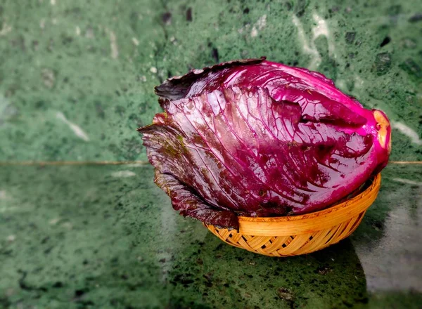 Küçük bir sepetteki taze kırmızı lahana taze yapraklı sebzeler.