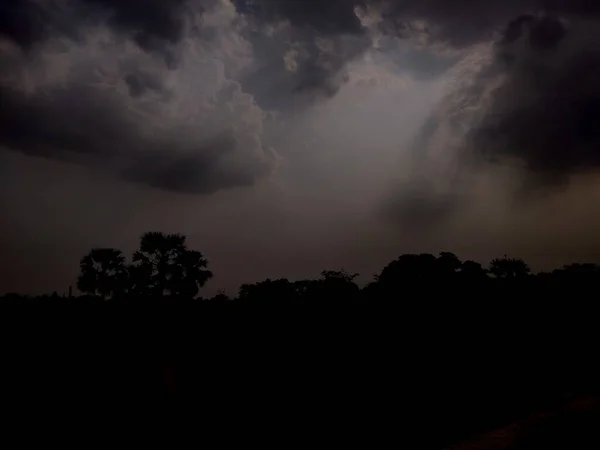 Yağmur mevsiminde bir Hint köyünde bulutlardan süzülen ışıltılı ışık demetleri.