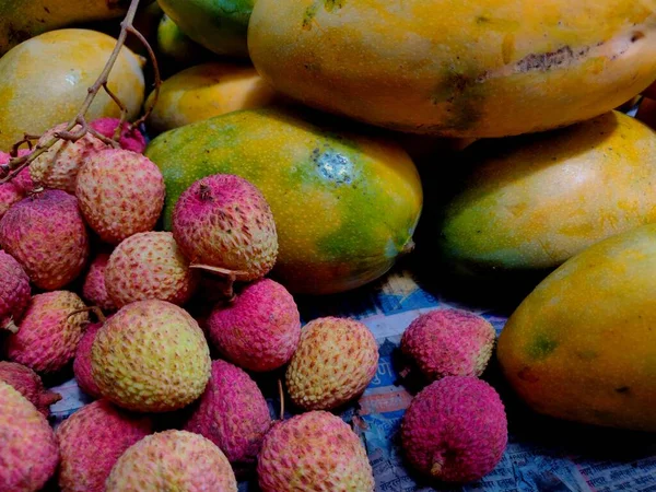 Lychee, Litchi chinensis ve mangolar gibi meyveler pazarda satılıktır.