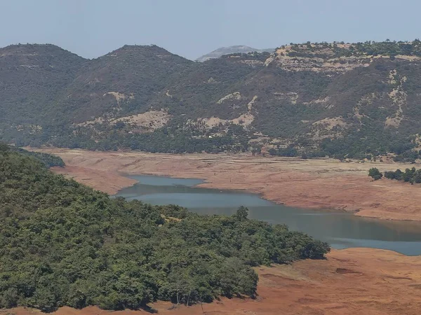 River Valley Panorama Vadisi. Su hatları, kahverengi toprak ve mavi gökyüzünün altındaki ormanlık yamaçlar mevsimsel kuraklığı ve güzelliği simgeliyor..