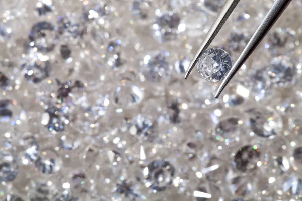 Diamante sostenido por pinzas de cerca. más diamantes fuera de foco en —  Fotos de Stock