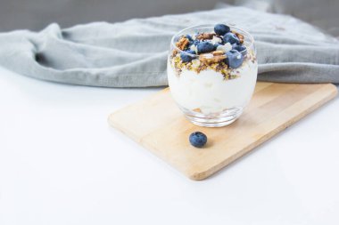 Sağlıklı yaban mersini ve beyaz arka planda bir bardakta cevizli parfe.