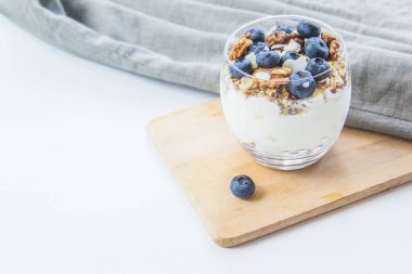 Sağlıklı yaban mersini ve beyaz arka planda bir bardakta cevizli parfe.