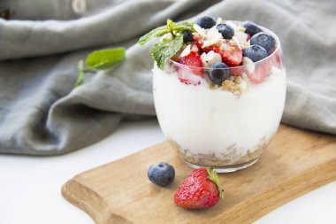 Sağlıklı yaban mersini ve beyaz arka planda bir bardakta cevizli parfe.