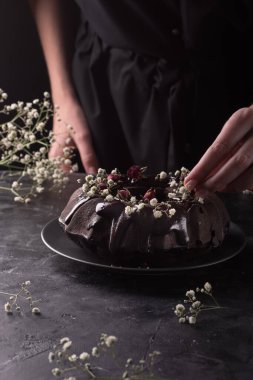 Kadın çikolatalı keki çiçeklerle süslüyor.