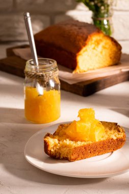 Bir kavanoz portakal reçeli ve beyaz bir masada bir pasta.