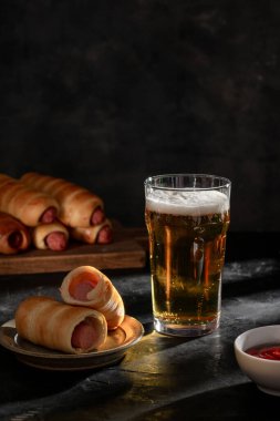 Hamurda ketçaplı büyük bir bardak light bira ve sosis.