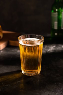 Siyah bir masada köpüklü bir bardak light bira.