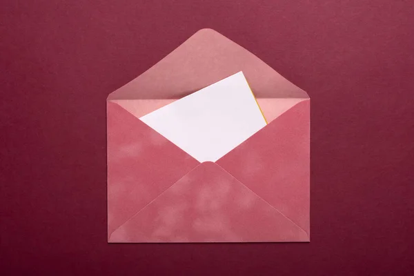バーガンディを背景にピンクの封筒 — ストック写真