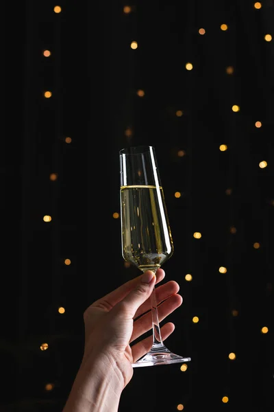 Champagne in woman\'s hand on a black background with bokeh