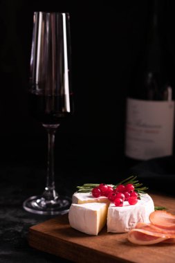 Camembert peyniri ahşap bir tahta ve kırmızı şarapla süslenmiş.