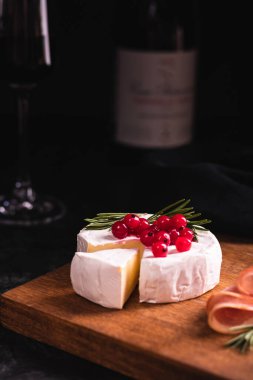 Camembert peyniri ahşap bir tahta ve kırmızı şarapla süslenmiş.