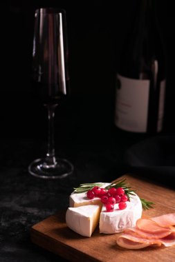 Camembert peyniri ahşap bir tahta ve kırmızı şarapla süslenmiş.