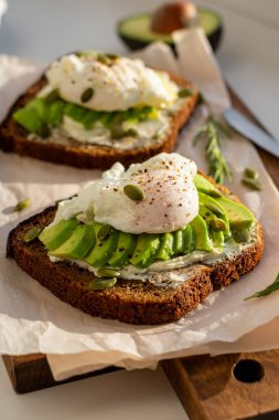 Kahvaltıda avokado ve yumurtalı iki sandviç.