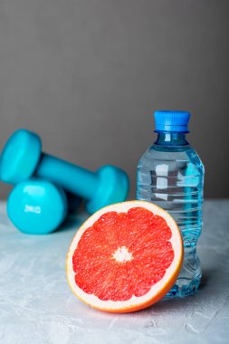 Dambıl, yarım greyfurt ve bir şişe su. Sağlıklı spor ve diyet kavramı.