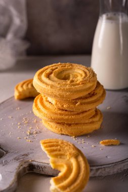 Vanilyalı kurabiyeleri ve beyaz tahta üzerinde bir fincan sütü kapat.