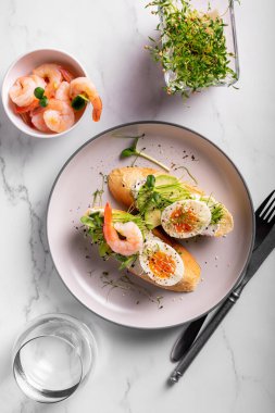 Bir tabakta karides, yumurta ve mikro yeşillik ve bruschetta ile kahvaltı.