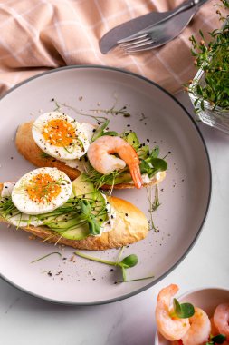 Bir tabakta karides, yumurta ve mikro yeşillik ve bruschetta ile kahvaltı.