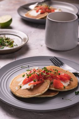Sabah kahvaltısı, somonlu krep ve gri tabakta mikro yeşillik.