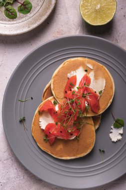 Sabah kahvaltısı, somonlu krep ve gri tabakta mikro yeşillik.