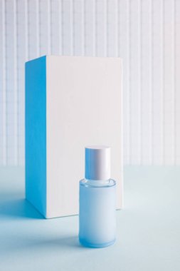 Mavi arka planda kozmetik şişesi ve beyaz küp