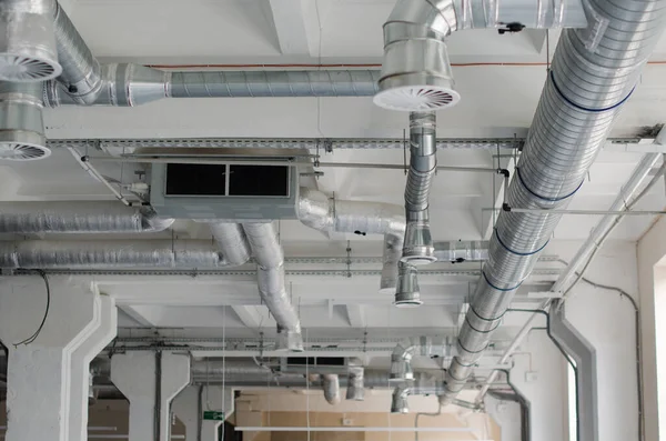 Air duct, air conditioner pipe on white ceiling wall. Ventilation system on the ceiling of large building. Air condition and hvac system installation under bareskin ceiling before interior finishing.