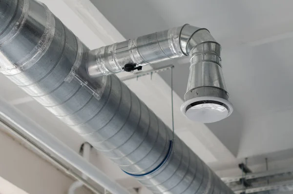 Ventilation system on the ceiling of large buildings. Ventilation pipes in silver insulation material hanging from the ceiling inside new building. Air flow and ventilation system. Building interior.