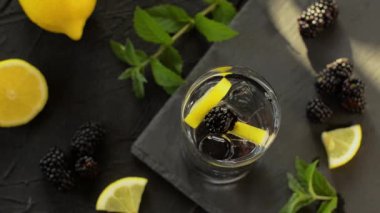 Yaz çalısı ve naneli kokteyl siyah taş masada bir bardakta. Soğuk mojito limonatasına bir dilim limon ekliyorum. Nane ferahlatıcı ve limonlu sağlıklı içecek. Üst görünüm.