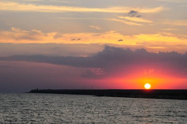 Karadeniz 'in üzerinde gün batımı. Bulutlar ve gökyüzü batan güneş tarafından farklı renklerde aydınlatılır. Güneş dünyanın kenarına değdi..