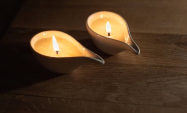 İki yanan mum ahşap bir masanın üzerinde duruyor.Bir mum yaşamın ve ışığın sembolü, sıcaklığın ve huzurun sembolü, bir yuva. Barış ve sağlık için dua. Boşluğu kopyala..