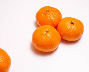 Üç kişilik bir grup ve bir parça mandalina. Beyaz arka planda tatlı, olgun narenciye meyveleri. Boşluğu kopyala..