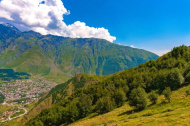 Georgia.Stepantsminda, Saint Stepan, Kazak Dağı eteklerinde bulunan bir köydür. Dağ sırası. Mavi gökyüzü beyaz bulutlarda..