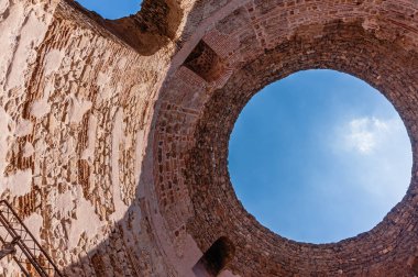 Split şehrindeki Jüpiter Tapınağı. Çatıda delik. Beyaz bulutlu mavi gökyüzü. Güneş duvarı aydınlatıyor..