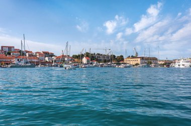 Hırvatistan. Trogir 'deki rıhtımda gemiler ve yatlar. Adriyatik Denizi 'nin turkuaz suyu. Manzaralı beyaz bulutlu mavi gökyüzü. Boşluğu kopyala.